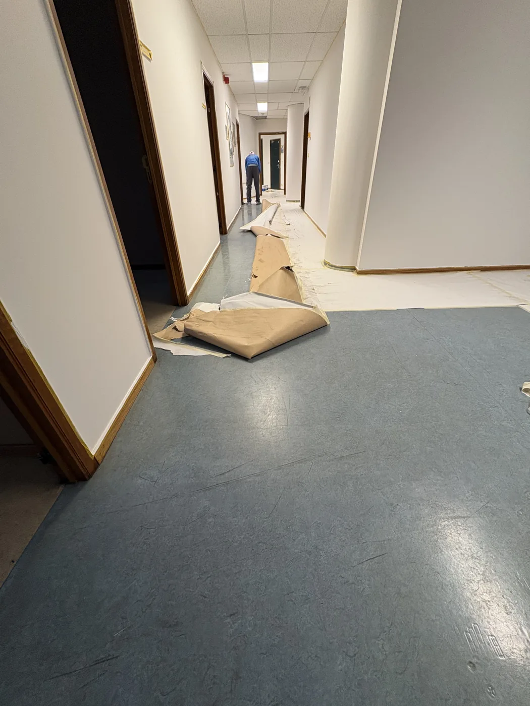 Couloir de bureaux avant intervention, revêtement de sol souple bleu à déposer
